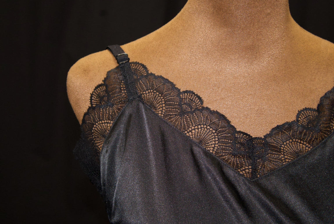 Black lace-trimmed camisole on a mannequin against a black background