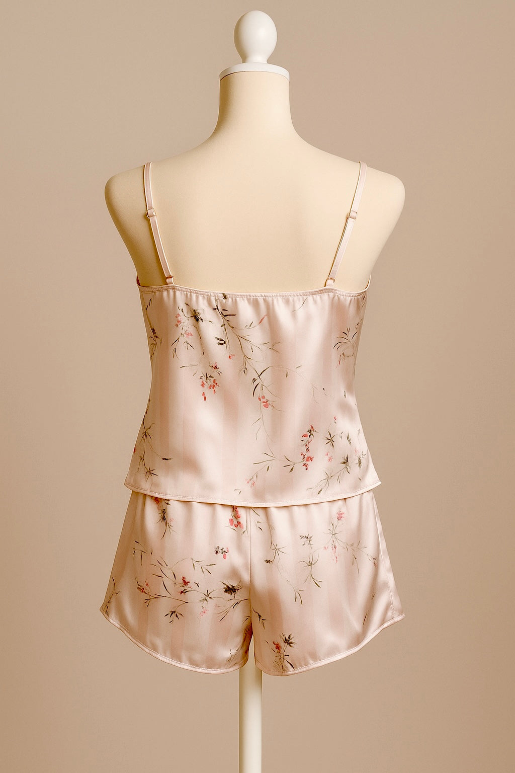 Silk pajama set with floral pattern on a mannequin against a beige background