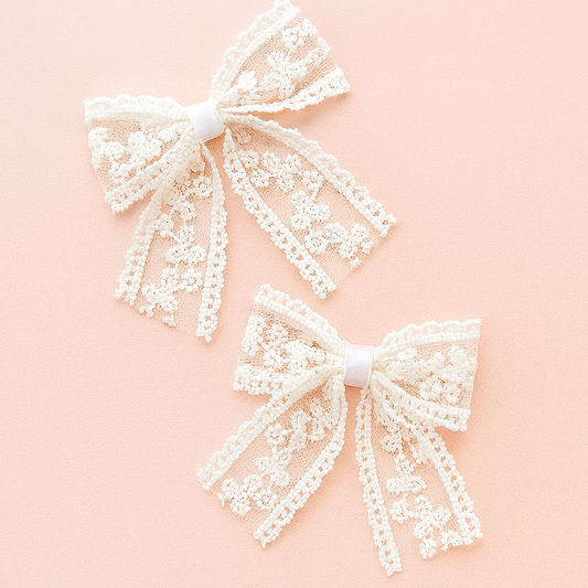 Two white lace bows on a pink background